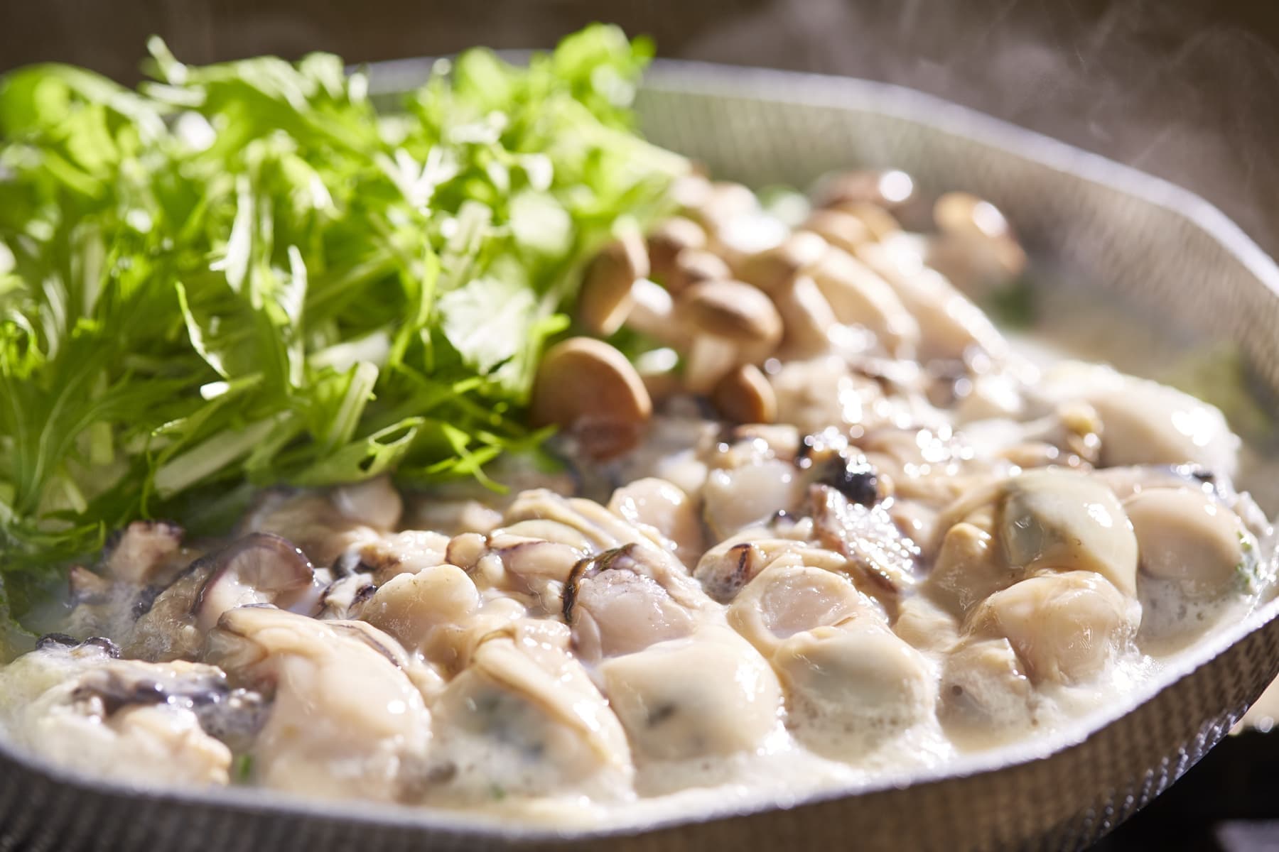 湯気が立ち上る牡蠣鍋の料理写真。温かさと食欲を引き出すシズル感を意識した料理撮影。